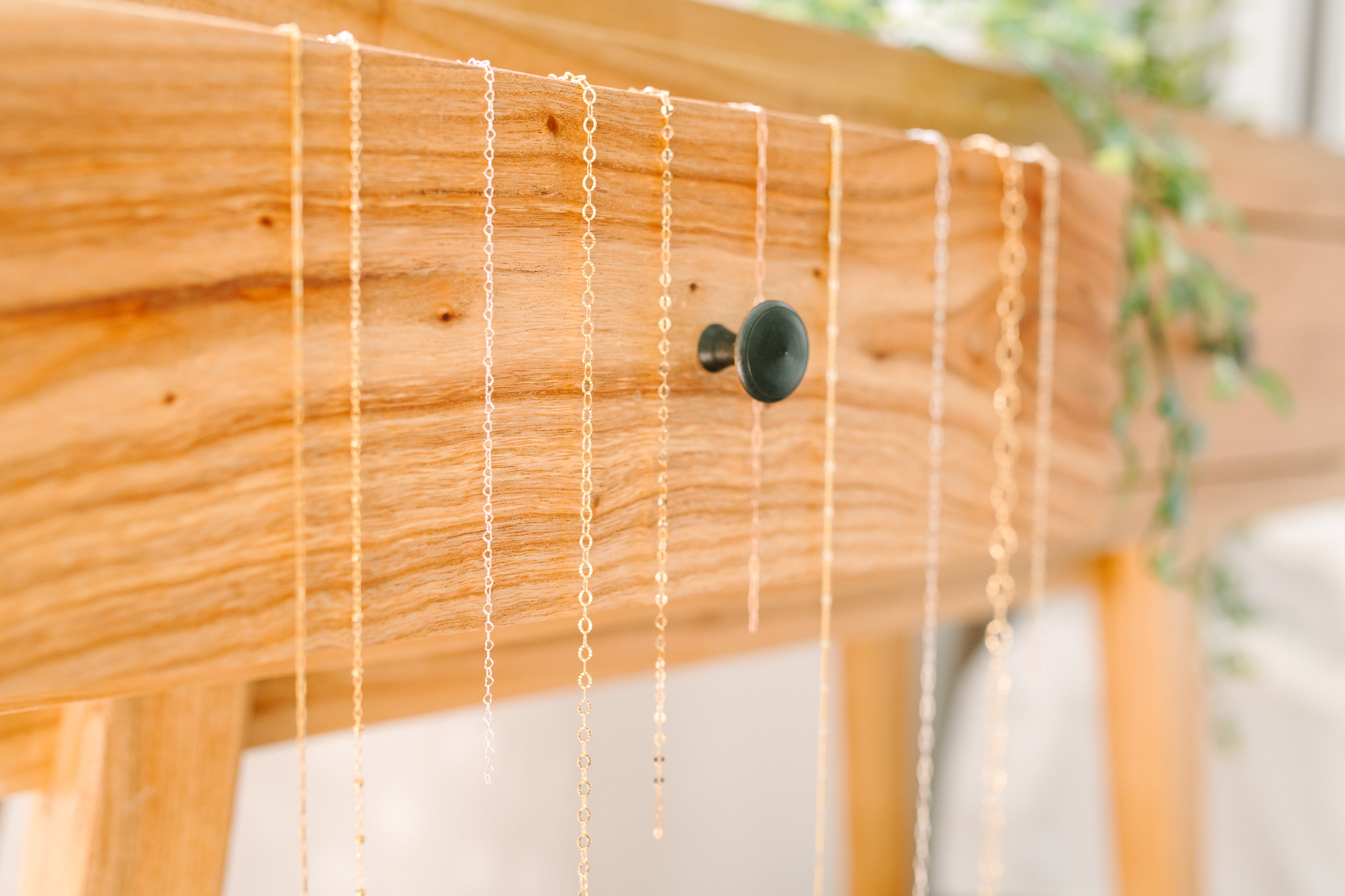 Necklaces hanging on a wooden surface with a blurred background